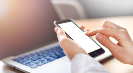 Girl pointing finger on blank screen cell phone wide banner, woman use cell phone, mockup white color background, Laptop computer blured keyboard.