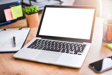 Modern laptop with white screen top view. Mockup computer blank display  workplace and cellphone detail at wooden table.