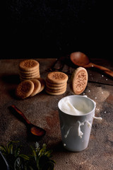 Fresh milk with homemade cookies on a wooden table, dark background.