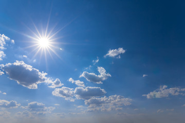 Naklejka na ściany i meble hot summer outdoor background, sparkle sun on a blue cloudy sky
