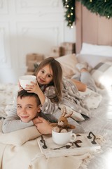Cheerful brother and sister in their bedroom decorated for Christmas 