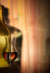 A glass of whiskey between the bottles