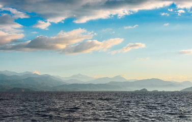 Stormy sea against the mountainous coast hiding in the haze.