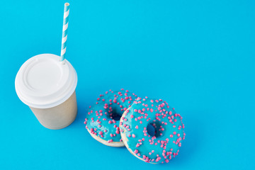Cup of coffee and donuts on a blue background, top view