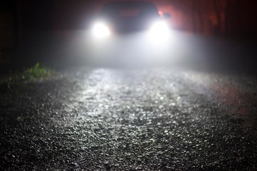 blurred car lights in foggy night. car traveling at night with focus on road.