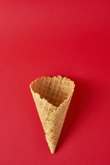 Empty ice cream cone on the red background, top view flat lay. Minimalism style creativity concept