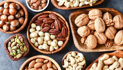 A variety of nuts in wooden bowls from top view. Walnuts, cashew, almond, pistachio, pecan, hazelnut, macadamia nut selection. Healthy super food.