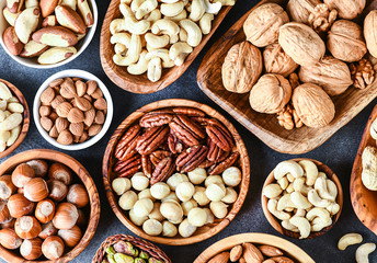 A variety of nuts in wooden bowls from top view. Walnuts, cashew, almond, pistachio, pecan, hazelnut, macadamia nut selection. Healthy super food.