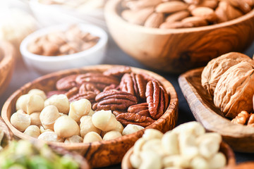 A variety of nuts in wooden bowls from top view. Walnuts, cashew, almond, pistachio, pecan, hazelnut, macadamia nut selection. Healthy super food.