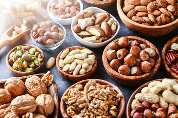 Mixed nuts in wooden bowls on black stone table. Almonds, pistachio, walnuts, cashew, hazelnut. Top view nut photo.