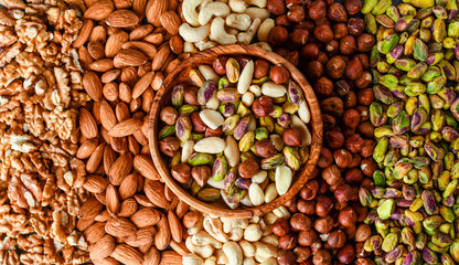 Mix nuts on dark stone table in line top view. Nut background, copy space for text concept.