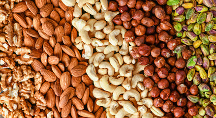 Mix nuts on dark stone table in line top view. Nut background, copy space for text concept.