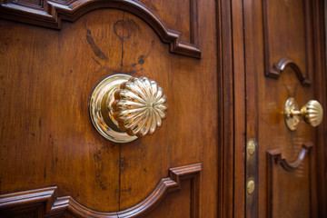 Exterior vintage door handle with a bronze finish on a wooden front door