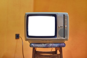 Vintage TV set on a chair with blank white screen