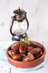 Ramadan lamp and dates still life. Raw sweet dry dates with in a terracotta bowl on a white background. Organic sweeties to healty eating