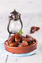 Ramadan lamp and dates still life. Raw sweet dry dates with in a terracotta bowl on a white background. Organic sweeties to healty eating
