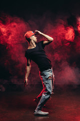 young vigorous male dancing isolated over red smoky space, wearing casual wear. street dance concept