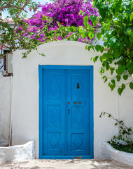 Old blue entrance door in whitewashed wall.