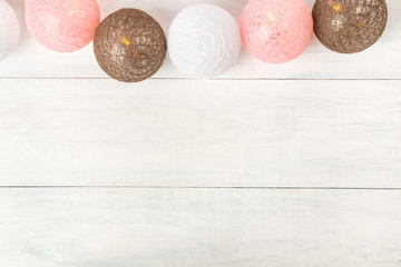 Garland of balls made of threads with yellow bokeh lights on white wooden planks. Beautiful cozy...