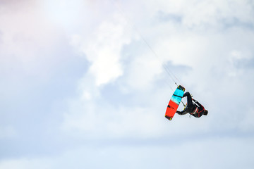Naklejka na ściany i meble Kite surfing. Kiter makes trick and fly in air on a cloud background.