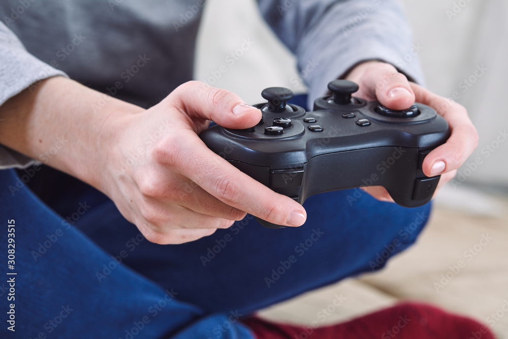 Poster man holding a joystick controllers while playing a video games at home