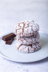 Chocolate cookies with cracks, strewed with icing sugar. Homemade baking. Three cookies in a stack. Selective focus, close-up.