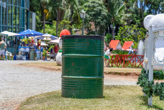 Old green metal barrels with party and few people.