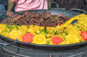 Large paella pan with separate meat, cooked in an outdoor area. One of the meals, with rice, most famous in Spain. Beautiful contrast of intense colors