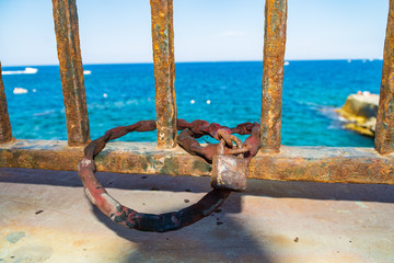 Fototapeta premium Chain and padlock on railings in front of the sea.