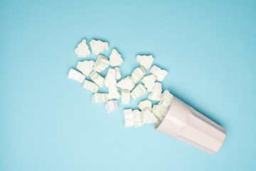 Cup full of Christmas marshmallows on a blue background.