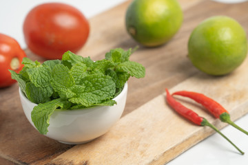peppermint in small cup on board and  Vegetable with white background