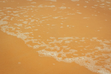 white sea foam on yellow sand, sea background, sandy beach