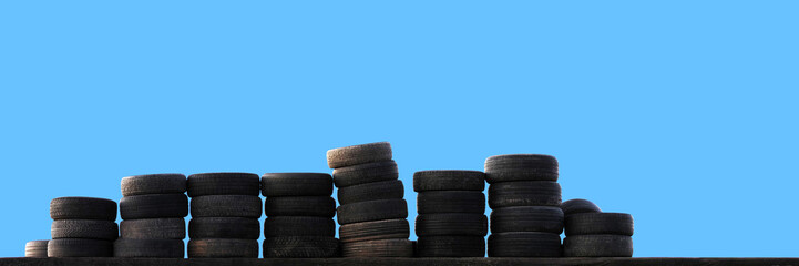 Fototapeta na wymiar Old tires stacked on blue sky background. Tire fitting, pile of car tires, panorama