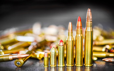 Various kind of bullets or ammonution on dark stone table. Bullet pile in color background. Magazines, rounds and ammo military technology.. - obrazy, fototapety, plakaty