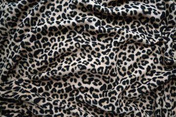 Trendy animal print background. Black and gold cheetah spots textured fabric with folds.