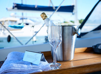 Romantic luxury evening on cruise yacht with champagne setting. Empty glasses and bottle with champagne and tropical sunset with sea background