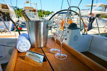 Romantic luxury evening on cruise yacht with champagne setting. Empty glasses and bottle with champagne and tropical sunset with sea background