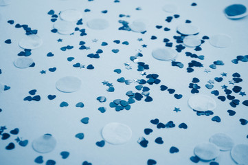 Defocused and blurred beautiful heart and stars shaped confetti on blue background. 2020 color trend.