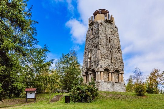 Zelena hora, Pelhrimov / Czech Republic - September 13 2019: Bismarck tower made of stone built in 19th century close to Cheb surrounded with green trees. Sunny day with blue sky and clouds.