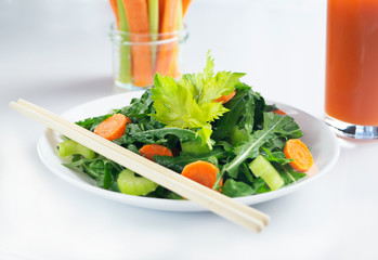 Fresh carrot celery arugula salad with olive oil served by chopsticks. Vegetarian natural food.