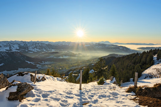 Sunset in the Bregenzerwald region with snow-covered mountains and hills under blue sky. Vorarlberg, Austria