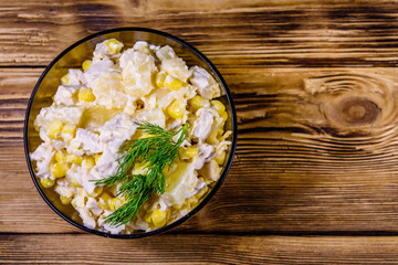 Festive salad with chicken breast, canned pineapple, cheese, sweet corn and mayonnaise on wooden table. Top view