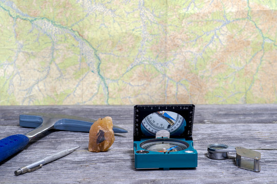 Tools geologist laid out on a wooden table on the background of a topographic map. Background