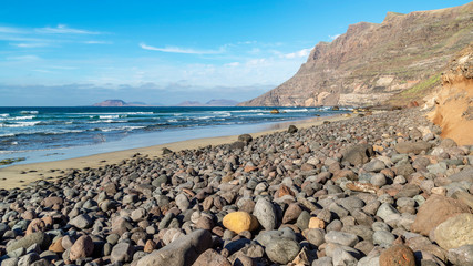 Fototapeta na wymiar Beautiful view of the pebble and sand beach of Famara, Lanzarote, Canary Islands, Spain