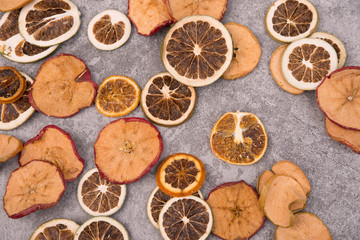 Dried lemon, orange and apple slices on a grey structured background