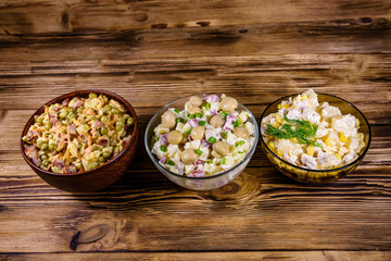 Set of festive mayonnaise salads on wooden table