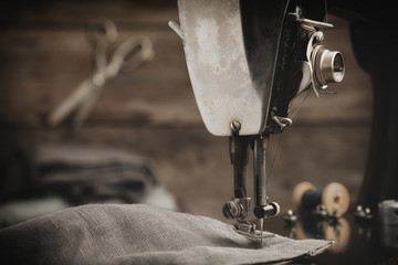 Old antique sewing machine with  linen cloth. In the background is a hanging tailoring scissors....