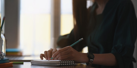 Side view attractive woman writing on notepad with pencil, Closeup shot.