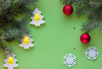 Christmas and New Year composition. Christmas tree branch decorated with Xmas lights, red balls, snowflakes, stars  on a green background. Flat lay, Top view.
