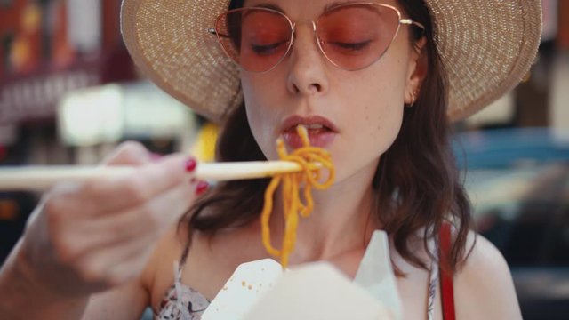 Young girl eating chinese noodles outdoors, close-up